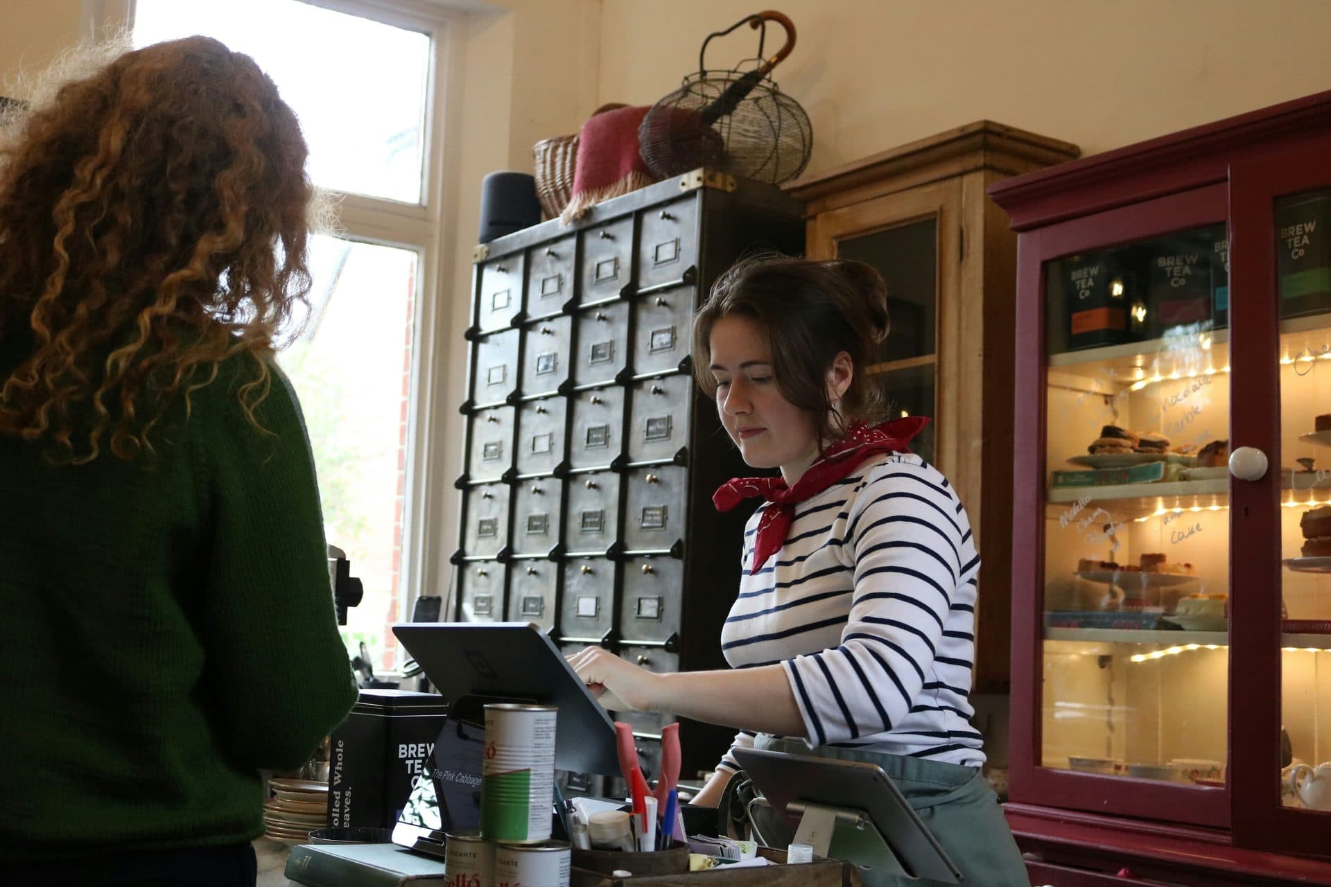 A cashier rings up a customer at a shop counter